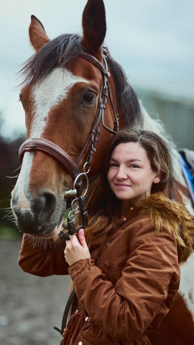 Prise de vue d'une adolescente à côté de son poney dans une ferme